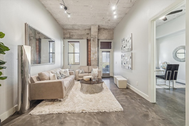 sitting room with track lighting, baseboards, and concrete flooring