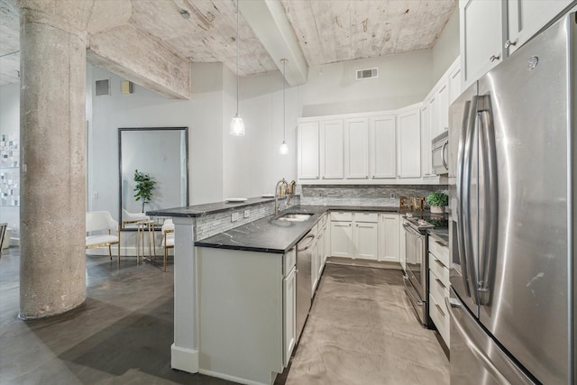 kitchen featuring dark countertops, visible vents, a peninsula, stainless steel appliances, and a sink