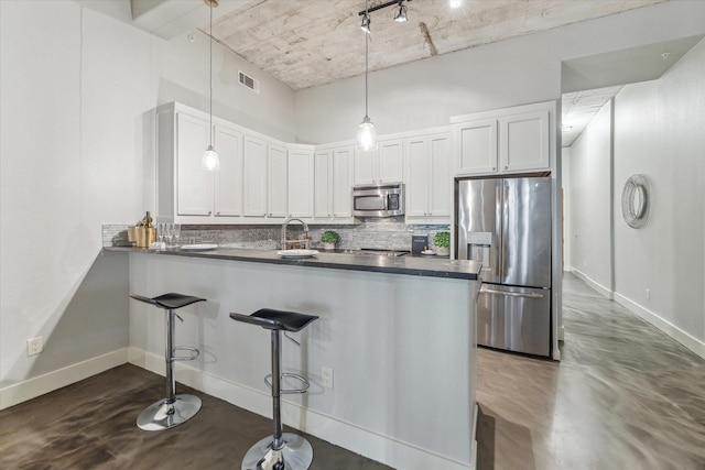 kitchen with visible vents, a peninsula, decorative backsplash, appliances with stainless steel finishes, and dark countertops