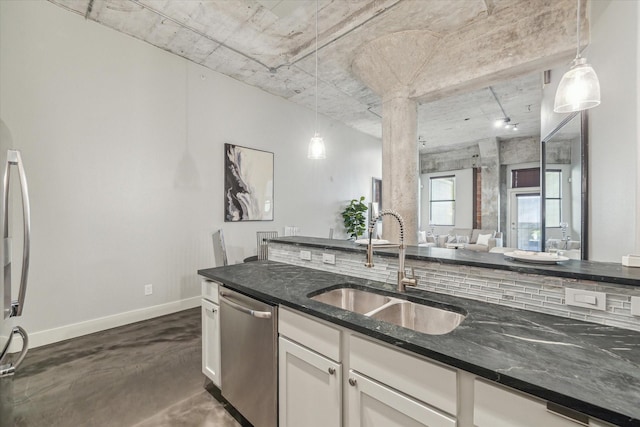 kitchen featuring pendant lighting, a sink, stainless steel dishwasher, dark stone counters, and baseboards