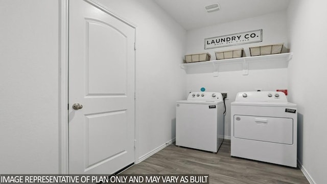 laundry area featuring laundry area, wood finished floors, visible vents, baseboards, and washer and clothes dryer