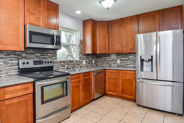 kitchen with a sink, tasteful backsplash, appliances with stainless steel finishes, and light tile patterned floors