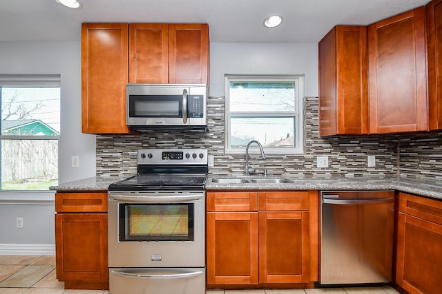 kitchen with a sink, stainless steel appliances, backsplash, and a wealth of natural light