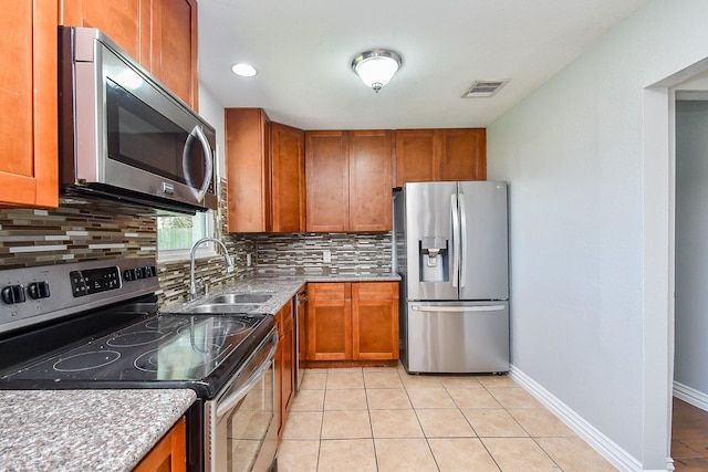 kitchen with decorative backsplash, light tile patterned floors, brown cabinets, and appliances with stainless steel finishes