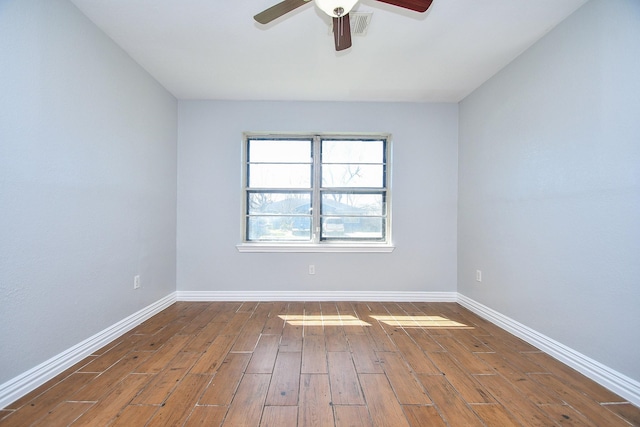 empty room featuring ceiling fan, visible vents, baseboards, and wood finished floors