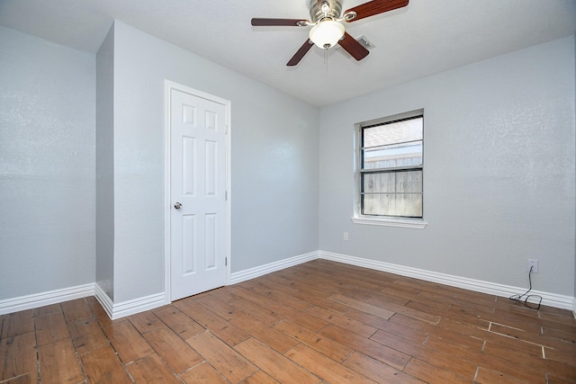 unfurnished room with baseboards, wood-type flooring, visible vents, and a ceiling fan