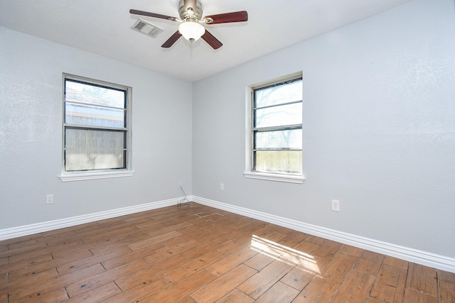 unfurnished room with visible vents, a ceiling fan, baseboards, and hardwood / wood-style flooring