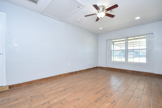 spare room with attic access, light wood-style floors, baseboards, and visible vents