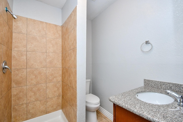 bathroom featuring vanity, baseboards, a tile shower, tile patterned flooring, and toilet