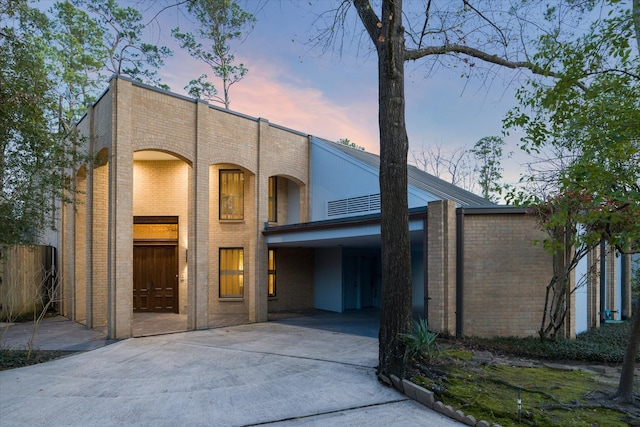 view of front facade with concrete driveway, brick siding, and fence