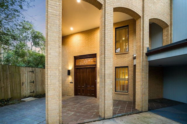 entrance to property with brick siding and fence