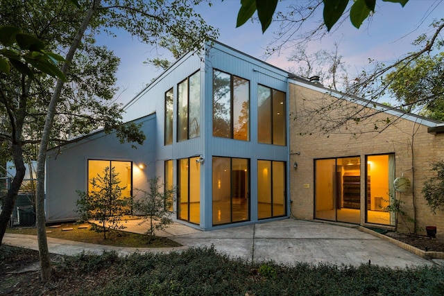 back of property at dusk featuring a patio