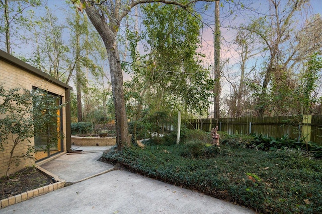 yard at dusk with fence and a patio