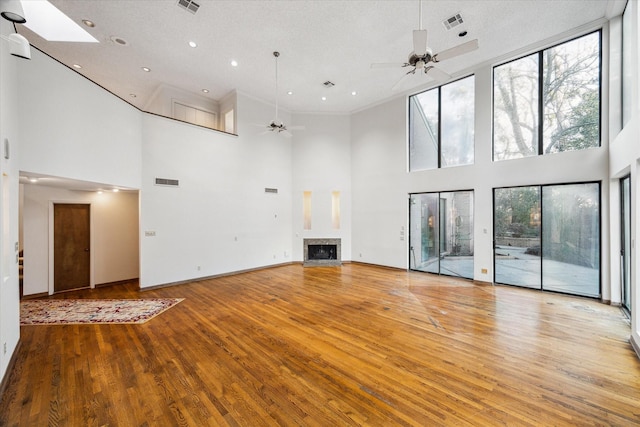 unfurnished living room featuring a ceiling fan, visible vents, a fireplace, and light wood-style flooring