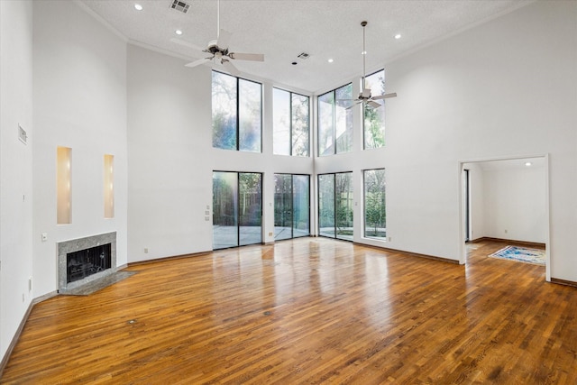 unfurnished living room with a premium fireplace, wood finished floors, a ceiling fan, and baseboards