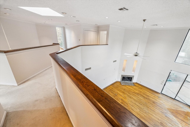 hall featuring a textured ceiling, an upstairs landing, visible vents, and crown molding