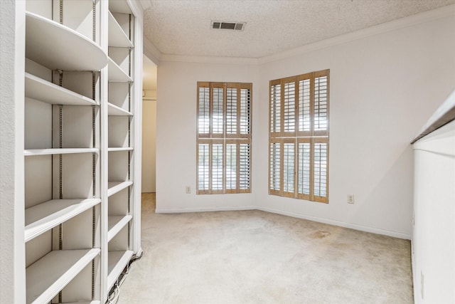 interior space featuring a textured ceiling, baseboards, visible vents, and crown molding