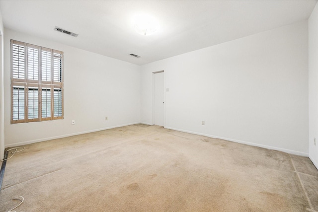 spare room featuring carpet, visible vents, and baseboards