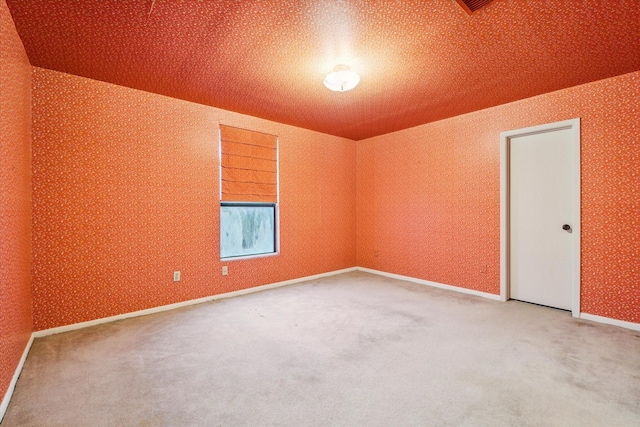 carpeted empty room featuring wallpapered walls and baseboards