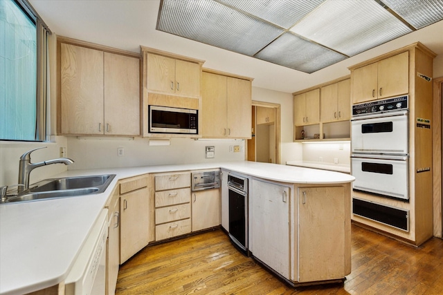 kitchen with white appliances, light brown cabinets, and a sink