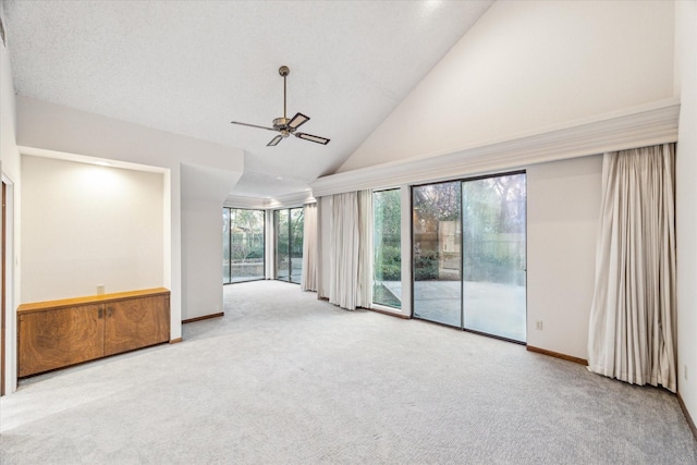 empty room featuring high vaulted ceiling, carpet flooring, ceiling fan, and baseboards