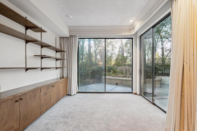 spare room with light carpet, a textured ceiling, and crown molding