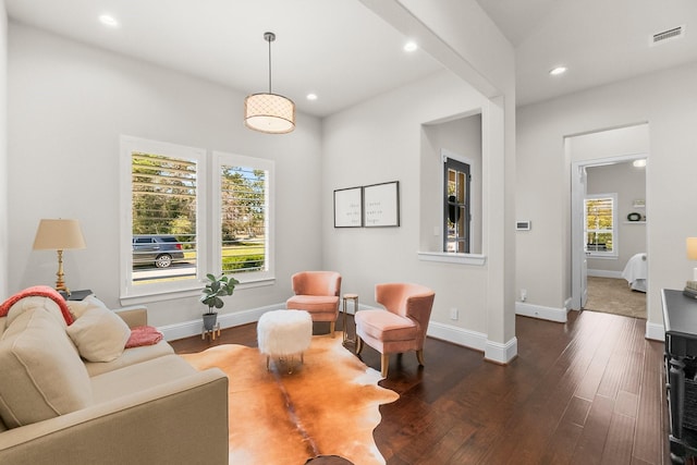 living area with dark wood-style floors, visible vents, baseboards, and a wealth of natural light