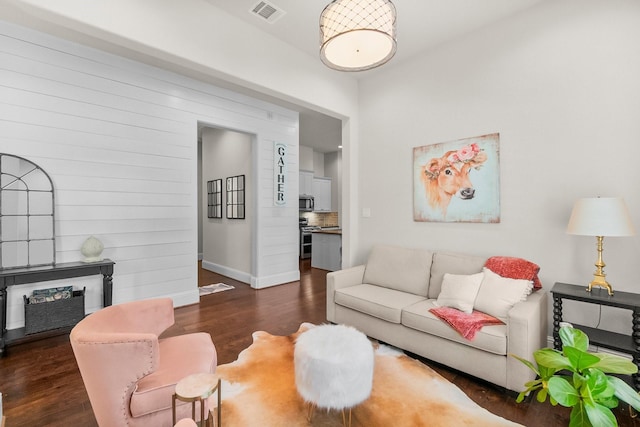 living area featuring wood finished floors, visible vents, and baseboards