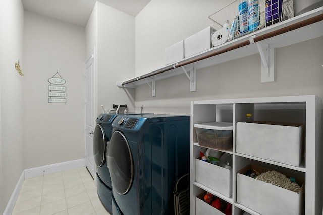 clothes washing area featuring laundry area, light tile patterned flooring, baseboards, and washer and clothes dryer