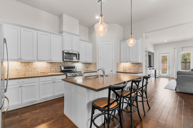 kitchen with a sink, decorative backsplash, dark wood-style flooring, and stainless steel appliances