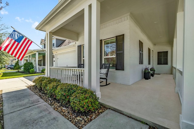 view of exterior entry featuring brick siding and covered porch