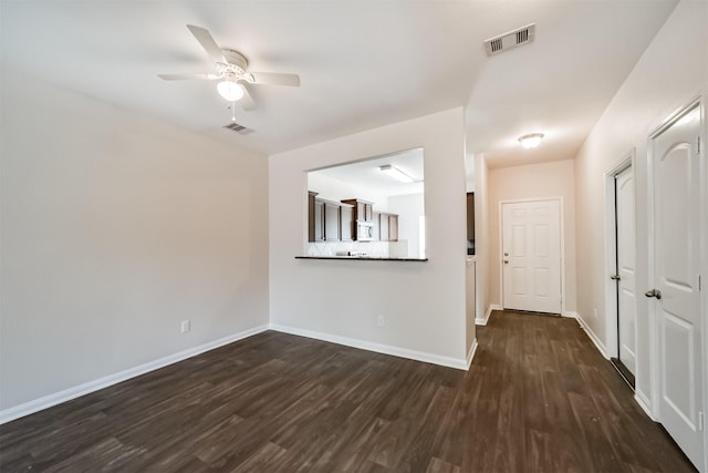 spare room featuring dark wood-type flooring, visible vents, and baseboards