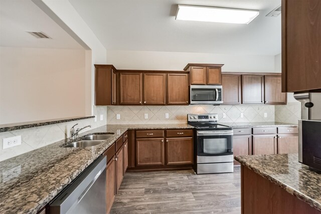 kitchen with visible vents, decorative backsplash, dark stone counters, stainless steel appliances, and a sink