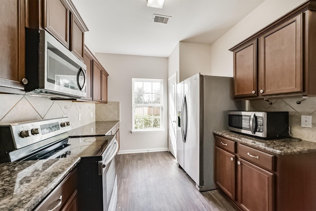 kitchen featuring dark stone countertops, visible vents, appliances with stainless steel finishes, and wood finished floors