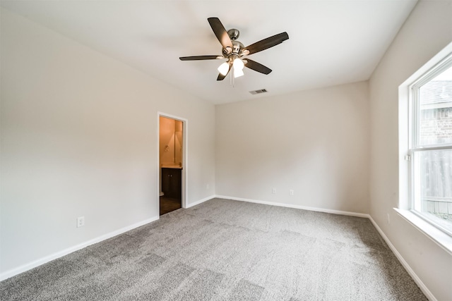 empty room with carpet floors, a ceiling fan, visible vents, and baseboards