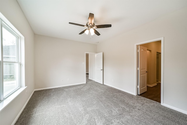 unfurnished bedroom with dark carpet, baseboards, and ceiling fan