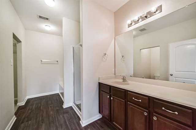 bathroom featuring vanity, wood finished floors, visible vents, and a shower stall