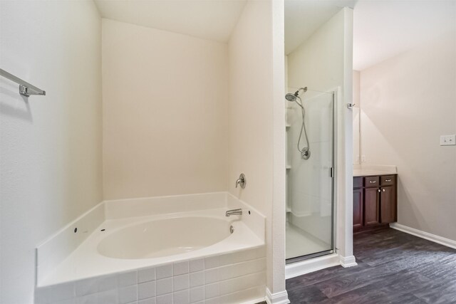 full bathroom featuring a stall shower, baseboards, wood finished floors, vanity, and a bath