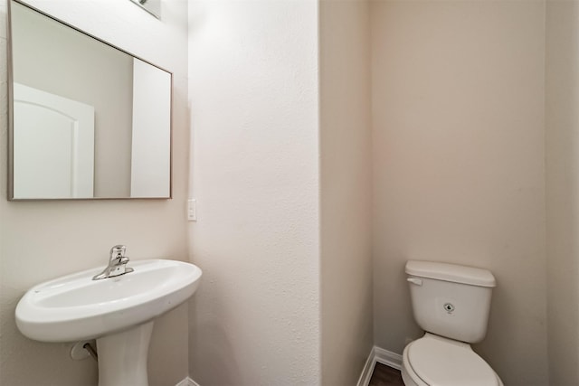 half bathroom featuring toilet and baseboards