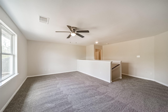 empty room with carpet floors, visible vents, ceiling fan, and baseboards