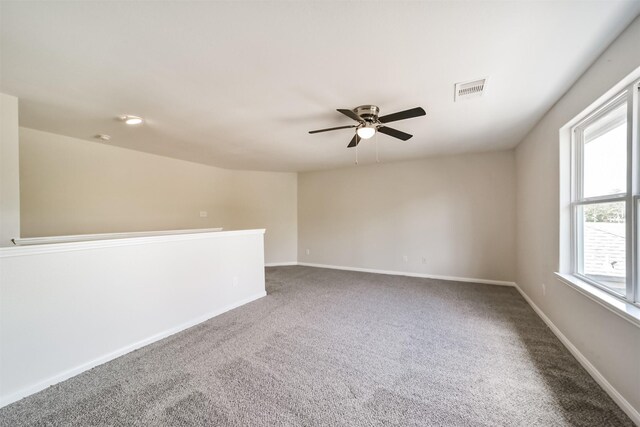 unfurnished room with carpet floors, visible vents, baseboards, and ceiling fan