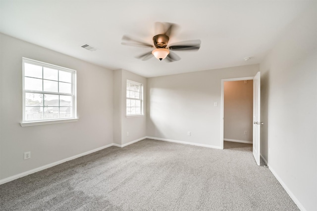 carpeted empty room featuring baseboards, visible vents, and a ceiling fan