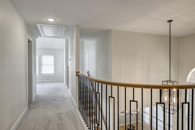 corridor with attic access, carpet flooring, and baseboards