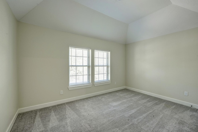 empty room featuring vaulted ceiling, carpet, and baseboards