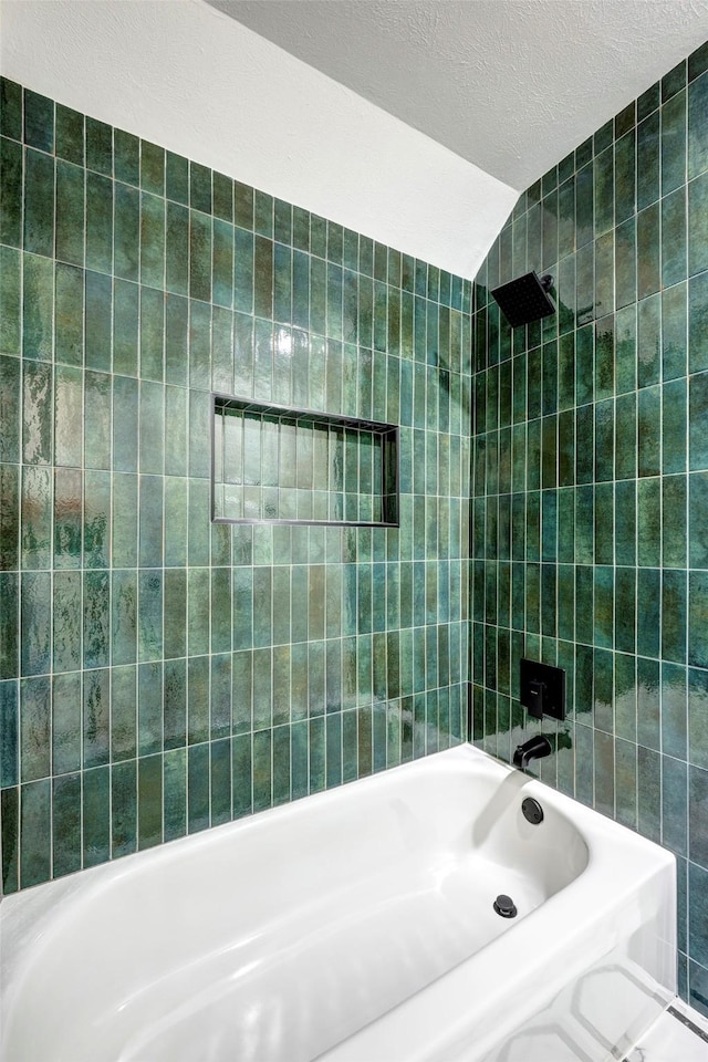 full bathroom featuring vaulted ceiling, a textured ceiling, shower / washtub combination, and tile walls