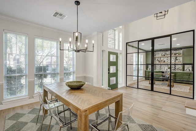 dining room featuring light wood-style floors, visible vents, a chandelier, and crown molding