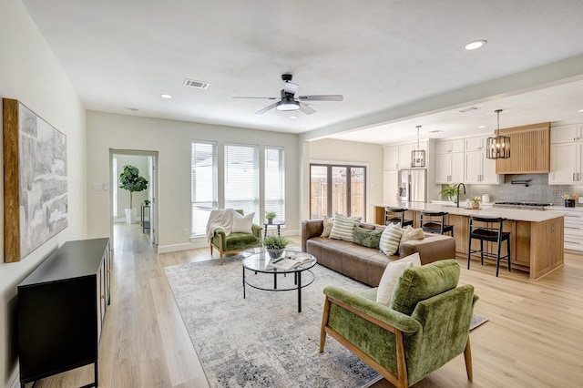 living room with baseboards, visible vents, a ceiling fan, light wood-style floors, and recessed lighting