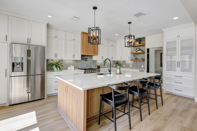 kitchen with open shelves, visible vents, a sink, light wood-type flooring, and stainless steel fridge with ice dispenser