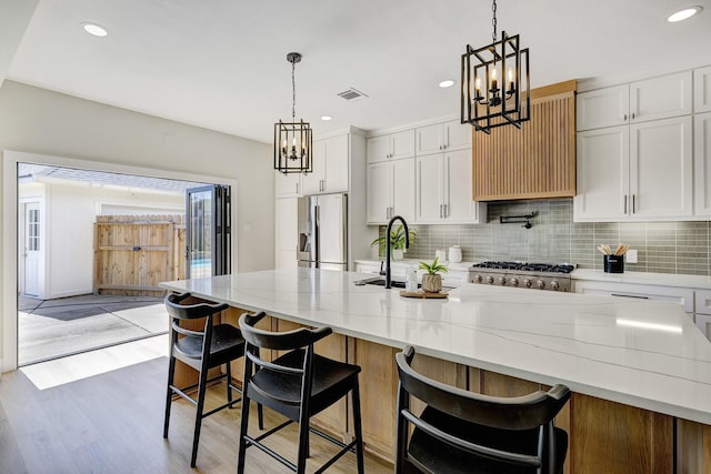 kitchen featuring tasteful backsplash, visible vents, stainless steel appliances, and a sink