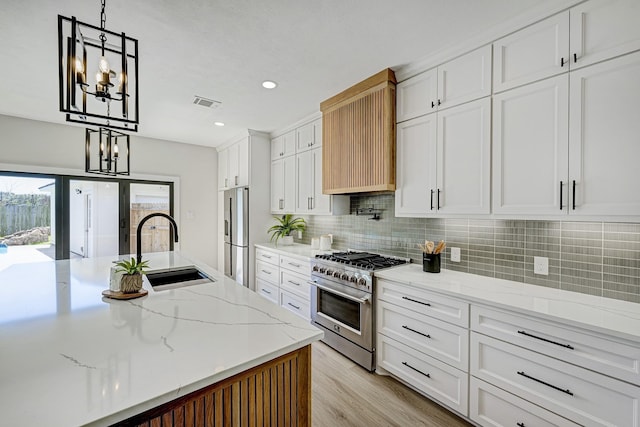 kitchen with a sink, visible vents, white cabinets, high end stainless steel range oven, and custom exhaust hood